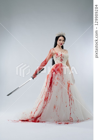 Bride in blood-soaked lingerie holds knife with a sinister aura 129989284