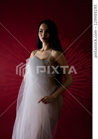 Beauty of a bride in elegant lingerie against a striking red background Beauty of a bride in elegant lingerie against a striking red background 129989295