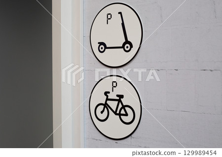 Parking signs for scooter and bicycle in urban environment. Clear and simple symbols indicating parking spots, ideal for city planning, urban transportation and sustainable mobility solutions Parking signs for scooter and bicycle in urban environment. Clear and simple symbols indicating parking spots, ideal for city planning, urban transportation and sustainable mobility solutions 129989454
