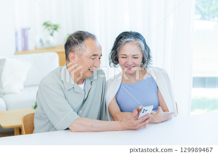 一對老夫婦在客廳裡看智能手機 129989467
