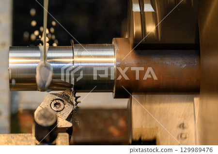 The lathe machine finish cut metal shaft parts with liquid coolant method. 129989476