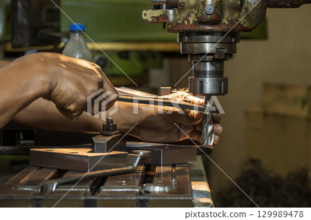 The machine operator changing the end mill tool on NC milling machine. The machine operator changing the end mill tool on NC milling machine. 129989478