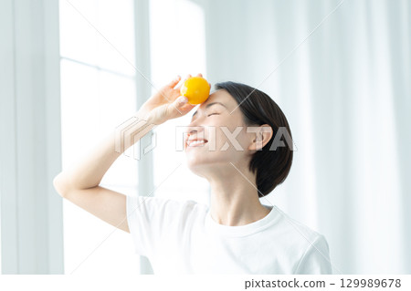A transparent woman holding a lemon in her hand and holding it to her forehead, upper body A transparent woman holding a lemon in her hand and holding it to her forehead, upper body 129989678