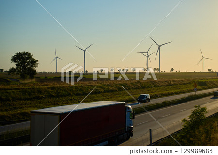 Trucks and cars on highway with wind turbines in background 129989683