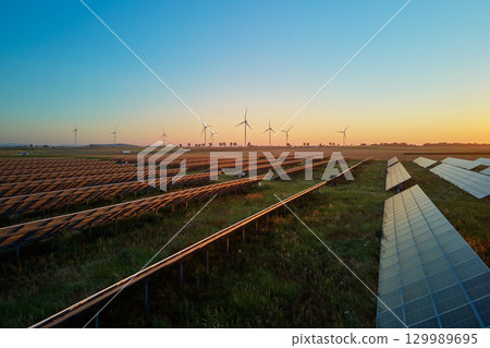 Solar panels and wind turbines at sunset. Renewable energy production 129989695