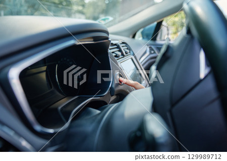 Hand pressing car engine start button inside modern vehicle 129989712