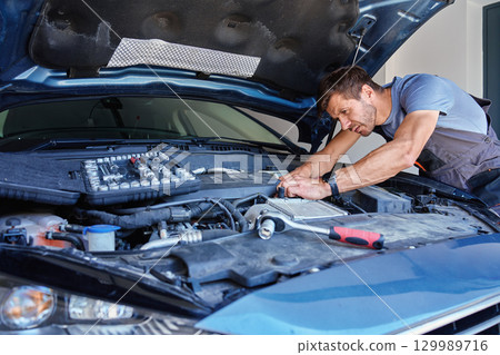 Mechanic holding wrench over car engine during repair Mechanic holding wrench over car engine during repair 129989716