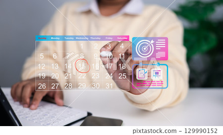 Close up of person using transparent digital calendar with highlighted date and floating icons for goals, task management, and project planning, concept of time management and productivity. 129990152