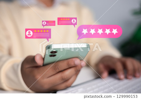 Close up of hand holding smartphone with five star rating and customer review icons, concept of online feedback, business reputation, and digital customer experience. Close up of hand holding smartphone with five star rating and customer review icons, concept of online feedback, business reputation, and digital customer experience. 129990153