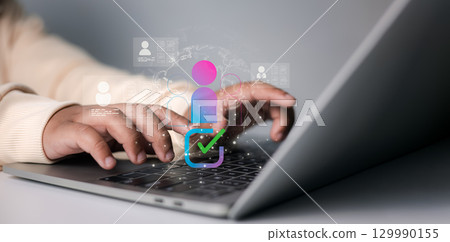 HR manager typing on laptop with digital employee profile and verification icon, concept of recruitment, workforce management, and online human resources system. 129990155