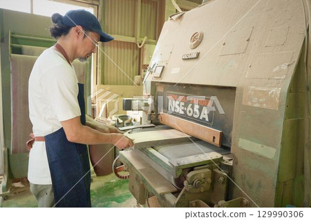 Senior craftsman performing polishing work at a woodworking shop 129990306
