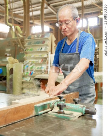 A veteran craftsman working with wood at a woodworking shop 129990310