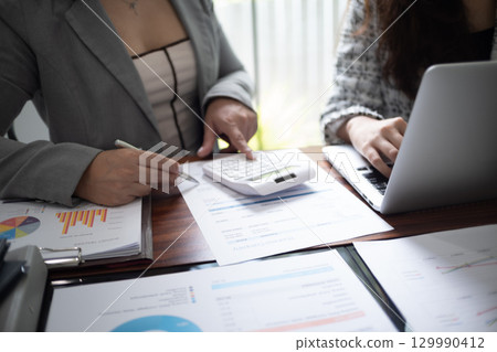 Businesswoman, entrepreneur, accountant working on financial report on desk using calculator, laptop. 129990412