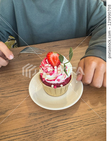 Juicy strawberry cupcakes crowned with airy whipped cream and decorated with vibrant fresh strawberries, offering a delightful blend of flavor and visual appeal ideal for summer treats. 129990708