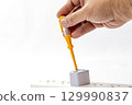 Hand using voltage tester on electrical socket safety check white background close up precaution electrical tool home maintenance testing careful indoor scene 129990837