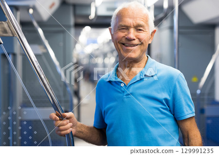 Old man standing in subway car 129991235