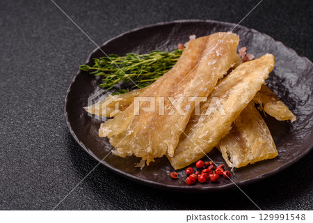 Dried salted fish, snacks or jerky, slices of white fish fillets 129991548