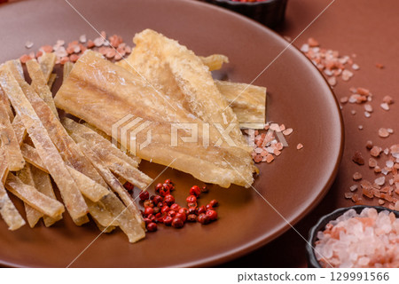 Dried salted fish, snacks or jerky, slices of white fish fillets 129991566