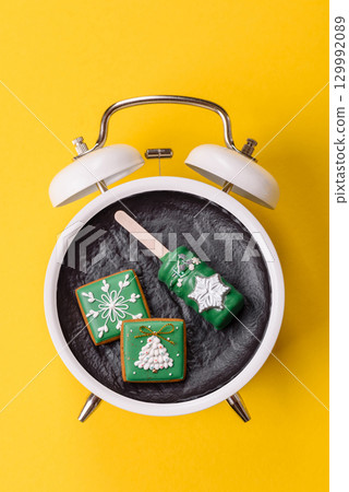 Christmas, eclair on a plate on a vintage clock. Christmas time conceptual background Christmas, eclair on a plate on a vintage clock. Christmas time conceptual background 129992089
