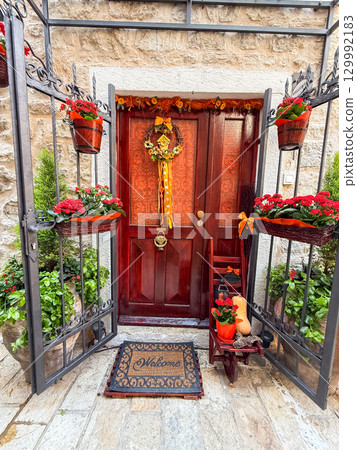 Decorated wooden door with floral wreath and seasonal details. Home entrance, culture, hospitality, tradition and lifestyle in a historic European town. Decorated wooden door with floral wreath and seasonal details. Home entrance, culture, hospitality, tradition and lifestyle in a historic European town. 129992183