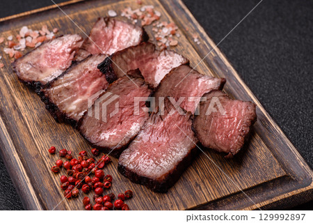 Grilled beef steak meat with salt and pepper. Beef steak grilled on a barbecue Grilled beef steak meat with salt and pepper. Beef steak grilled on a barbecue 129992897
