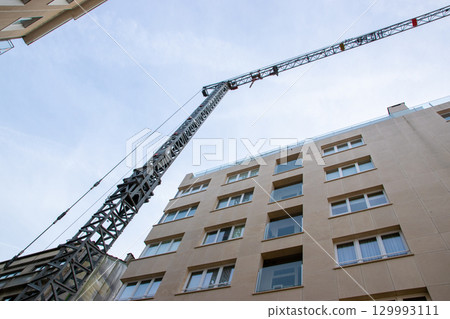 Metal building crane outside. Look above from backyard of an house to the roof opening with windows, walls, un the sun light. Metal building crane outside. Look above from backyard of an house to the roof opening with windows, walls, un the sun light. 129993111