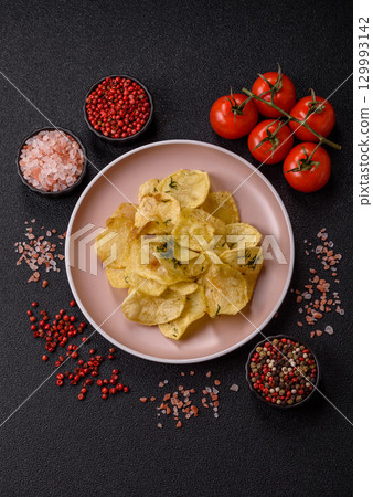 Crisps fried with salt, spices and garlic. Cooked potatoes 129993142