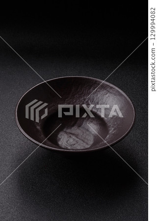 Empty round black plate for food, risotto or pasta. Empty plate on dark background Empty round black plate for food, risotto or pasta. Empty plate on dark background 129994082