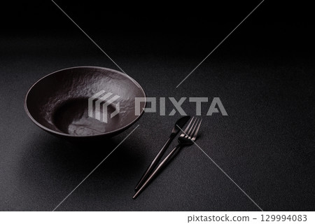 Empty round black plate for food, risotto or pasta. Empty plate on dark background Empty round black plate for food, risotto or pasta. Empty plate on dark background 129994083