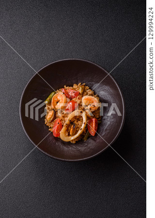 Rice and prawns or paella, a meal with seafood and vegetables. Cooked rice with shrimp Rice and prawns or paella, a meal with seafood and vegetables. Cooked rice with shrimp 129994224