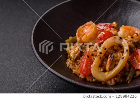 Rice and prawns or paella, a meal with seafood and vegetables. Cooked rice with shrimp 129994226