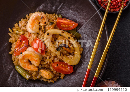 Rice and prawns or paella, a meal with seafood and vegetables. Cooked rice with shrimp 129994230