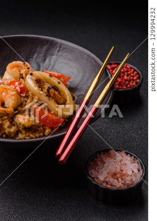 Rice and prawns or paella, a meal with seafood and vegetables. Cooked rice with shrimp Rice and prawns or paella, a meal with seafood and vegetables. Cooked rice with shrimp 129994232