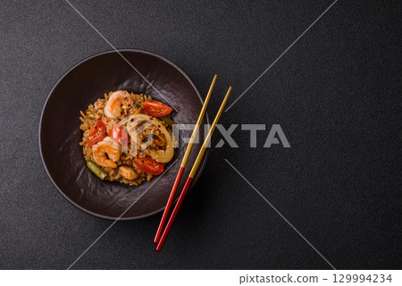 Rice and prawns or paella, a meal with seafood and vegetables. Cooked rice with shrimp 129994234