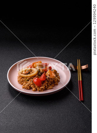 Rice and prawns or paella, a meal with seafood and vegetables. Cooked rice with shrimp 129994240
