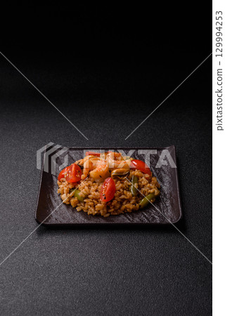 Rice and prawns or paella, a meal with seafood and vegetables. Cooked rice with shrimp 129994253