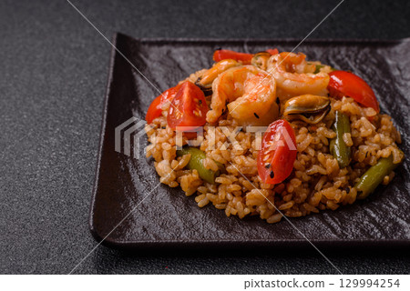Rice and prawns or paella, a meal with seafood and vegetables. Cooked rice with shrimp 129994254