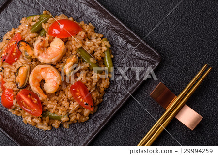 Rice and prawns or paella, a meal with seafood and vegetables. Cooked rice with shrimp Rice and prawns or paella, a meal with seafood and vegetables. Cooked rice with shrimp 129994259