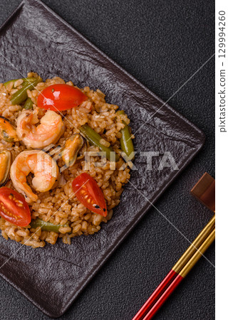 Rice and prawns or paella, a meal with seafood and vegetables. Cooked rice with shrimp 129994260