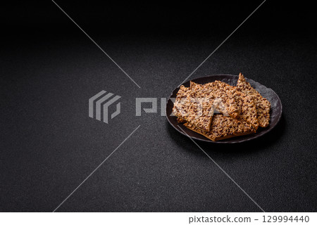 Crispbread, thin bread with seeds and grains, a baked cracker. Crispbread with sesame seeds Crispbread, thin bread with seeds and grains, a baked cracker. Crispbread with sesame seeds 129994440