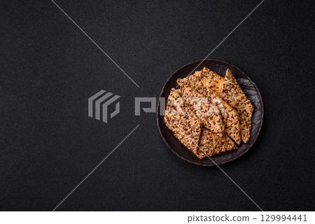 Crispbread, thin bread with seeds and grains, a baked cracker. Crispbread with sesame seeds 129994441