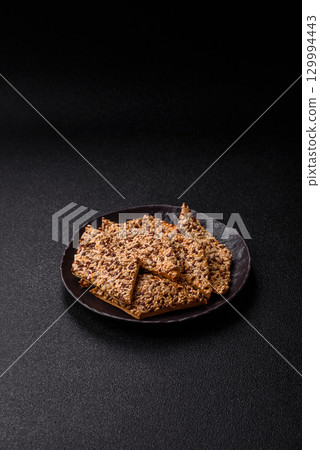 Crispbread, thin bread with seeds and grains, a baked cracker. Crispbread with sesame seeds Crispbread, thin bread with seeds and grains, a baked cracker. Crispbread with sesame seeds 129994443