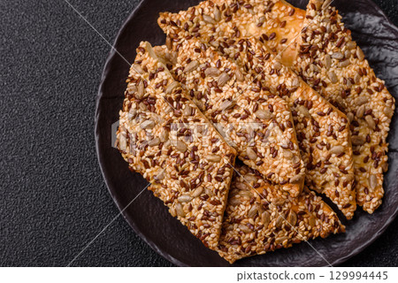 Crispbread, thin bread with seeds and grains, a baked cracker. Crispbread with sesame seeds Crispbread, thin bread with seeds and grains, a baked cracker. Crispbread with sesame seeds 129994445
