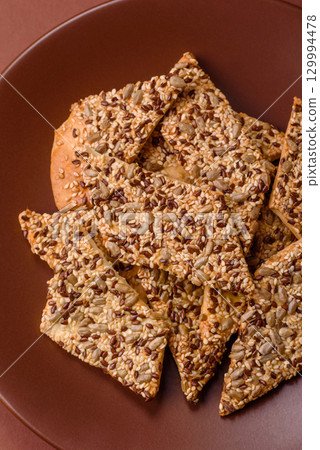 Crispbread, thin bread with seeds and grains, a baked cracker. Crispbread with sesame seeds Crispbread, thin bread with seeds and grains, a baked cracker. Crispbread with sesame seeds 129994478