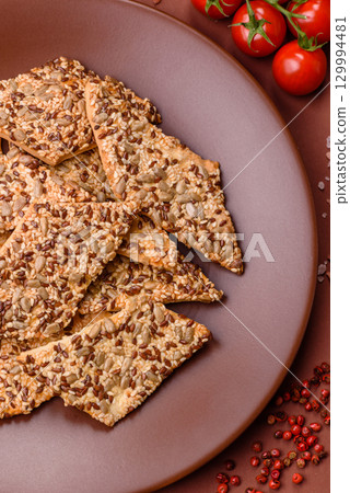 Crispbread, thin bread with seeds and grains, a baked cracker. Crispbread with sesame seeds Crispbread, thin bread with seeds and grains, a baked cracker. Crispbread with sesame seeds 129994481