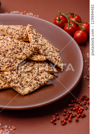 Crispbread, thin bread with seeds and grains, a baked cracker. Crispbread with sesame seeds Crispbread, thin bread with seeds and grains, a baked cracker. Crispbread with sesame seeds 129994482