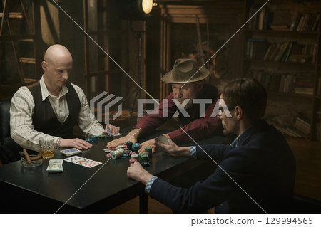 Male company enjoying a table game in a smoky library 129994565