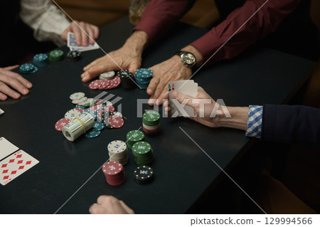 Men enjoying poker game with colorful chips and cards together 129994566