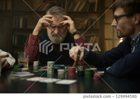 An intense poker game in a vintage library featuring men company 129994580