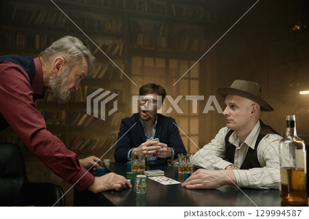 Determined man tensely making his move in a poker game in a vintage bar 129994587